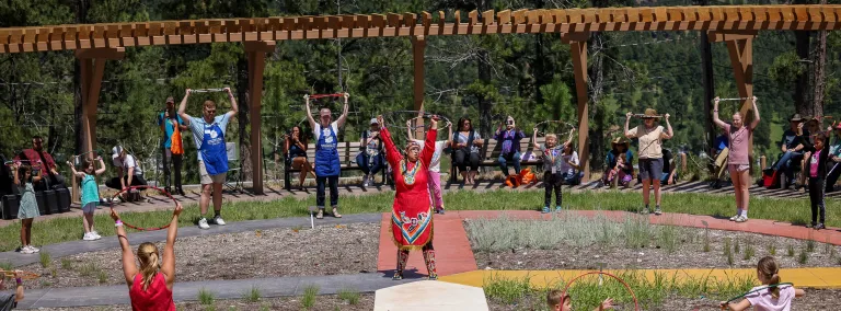A group of people learning the basics of hoop dancing at the garden at SURF.