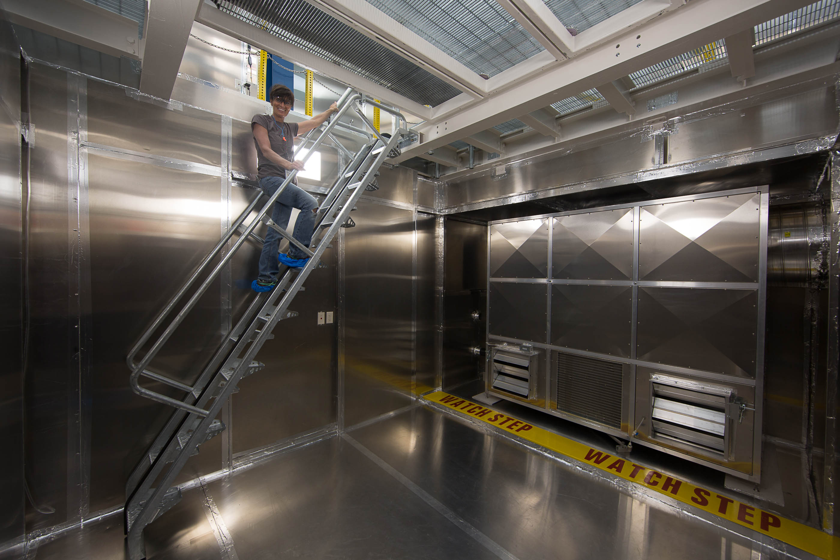 A woman stands on stair in a pit under the clean room