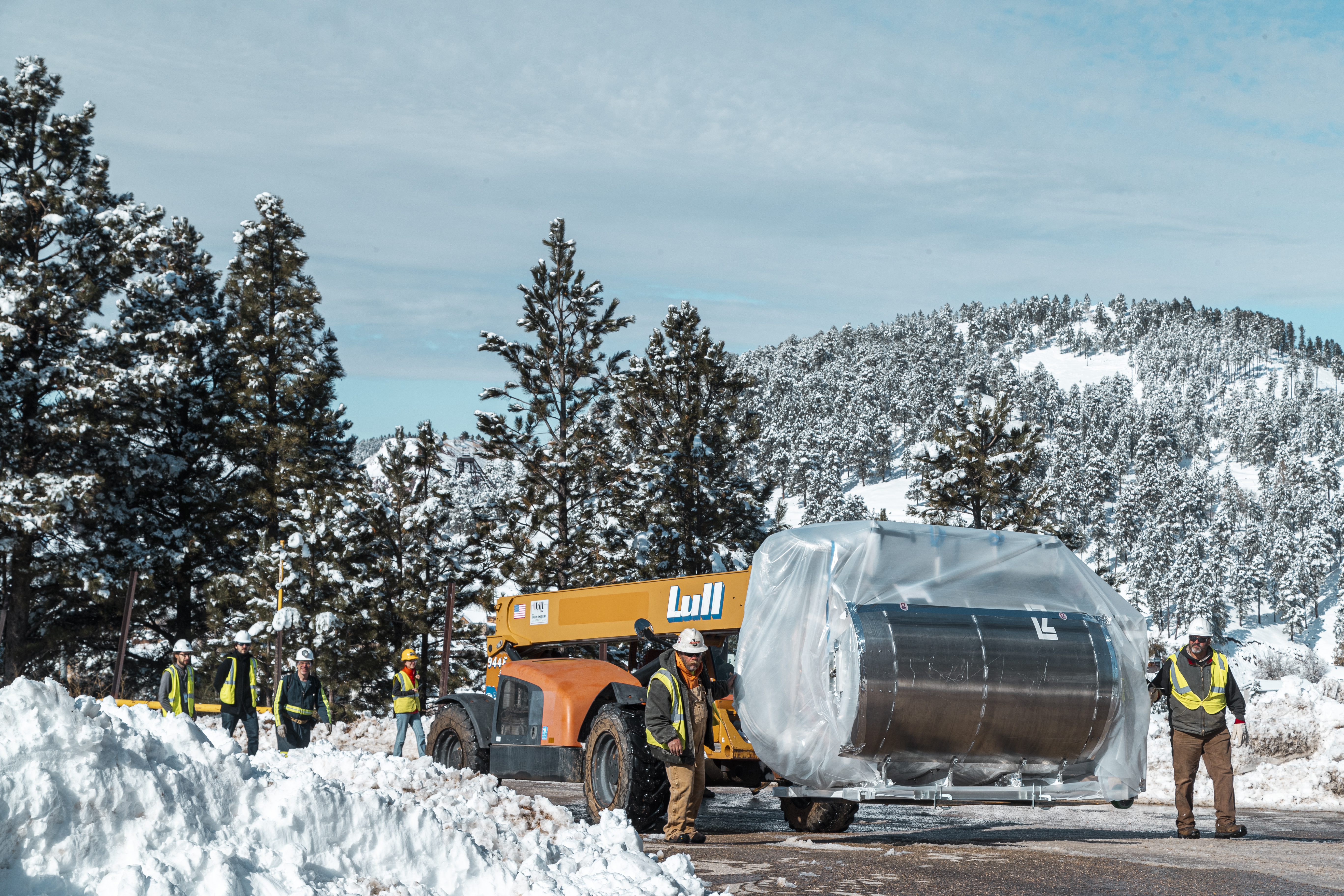 people walk alongside the forklift that is carrying the LZ detector