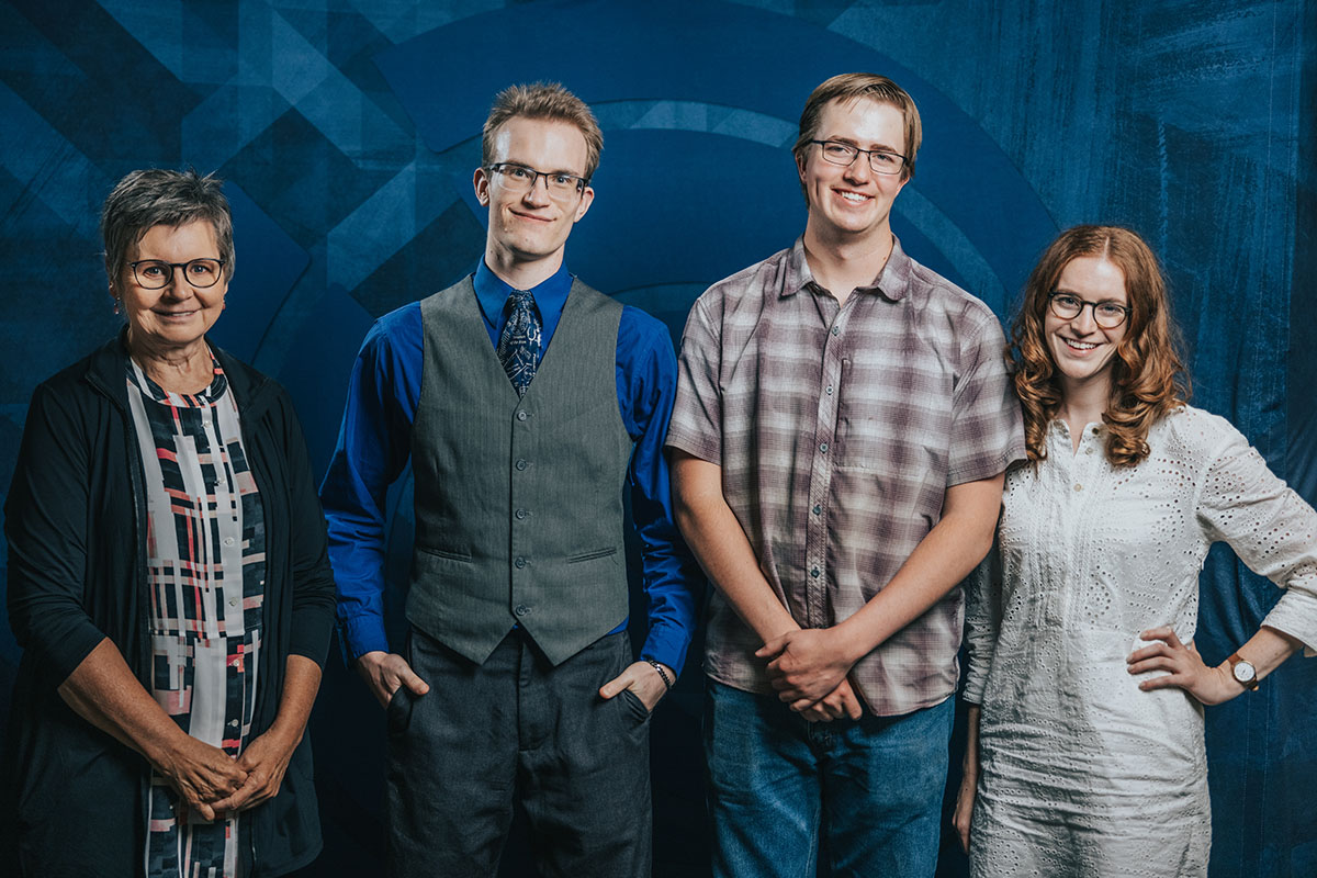 four people stand in front of a dark blue background