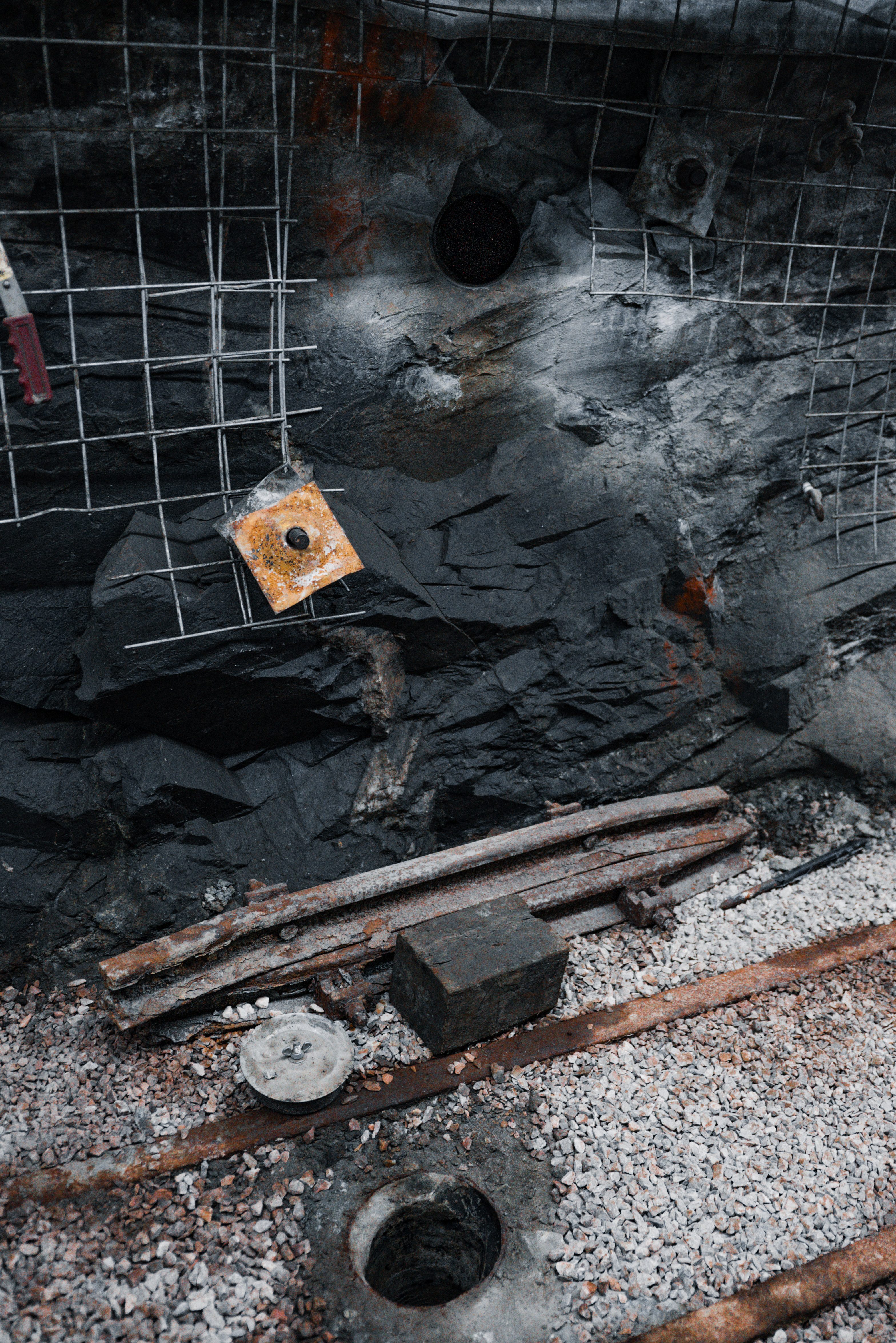 Photo of a drift wall, with two boreholes: one in the wall and one in the floor.