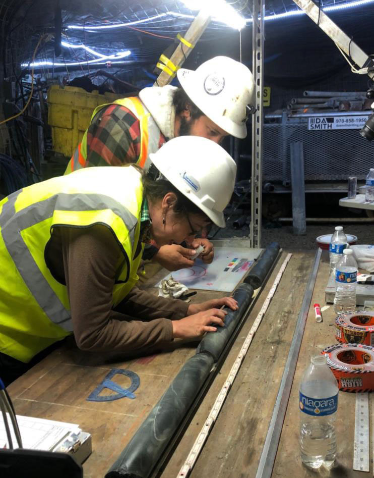 two researchers examine a core sample on a table underground