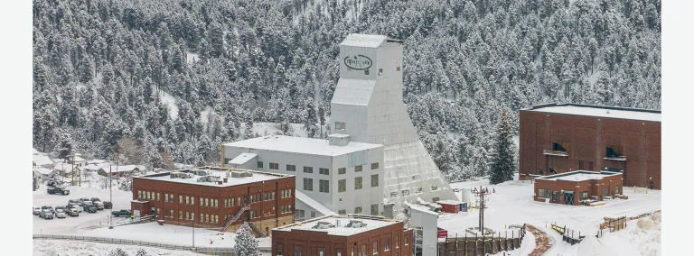 The Yates Shaft and administration buildings at the Sanford Underground Research Facility (SURF) on a cold morning surrounded in snow and frost covered trees.