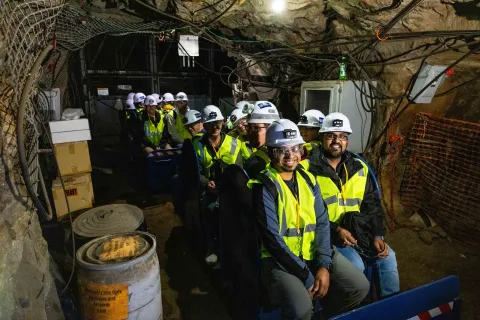 Some members of the CUSSP collaboration on board a mine rail cart headed for the geothermal test bed laboratory on the 4100 Level of SURF. members are wearing bright vests, hard hats, lights and PPE.
